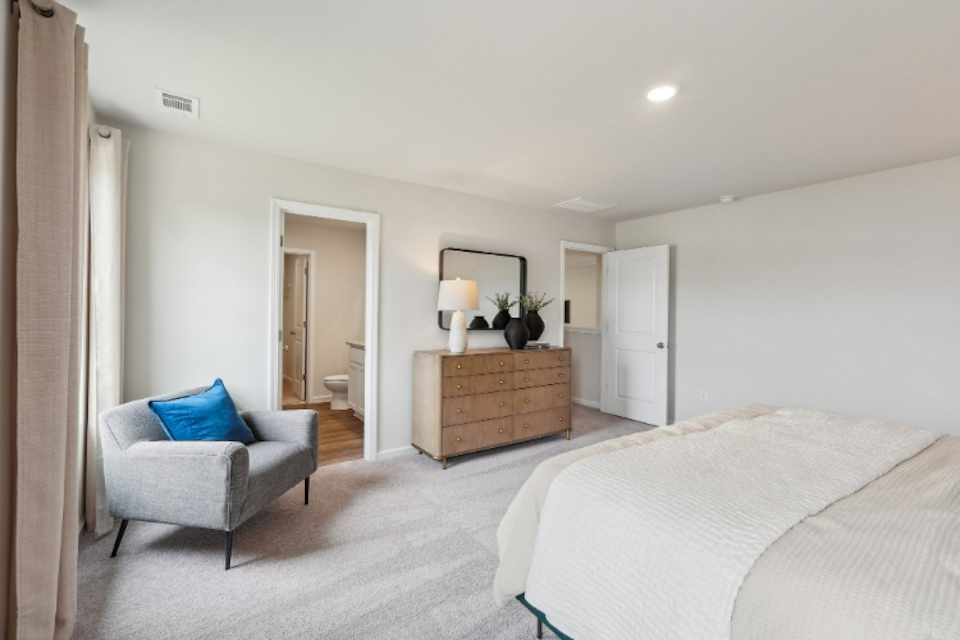 A bedroom with a bed and a chair.