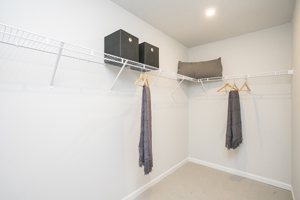 A white room with a white wall and a black rectangular object from the ceiling.