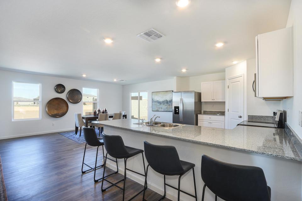 A kitchen with a bar and chairs.