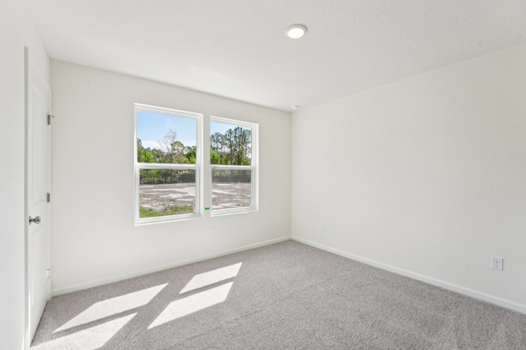 A room with a window and a white wall with a white door.